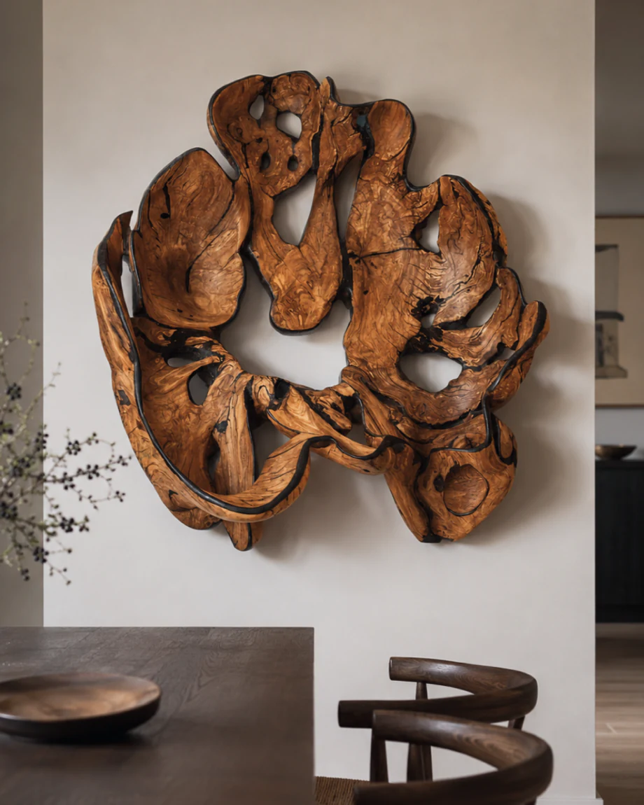 Root wood sculpture installed on a pale wall beside a dark dining table.